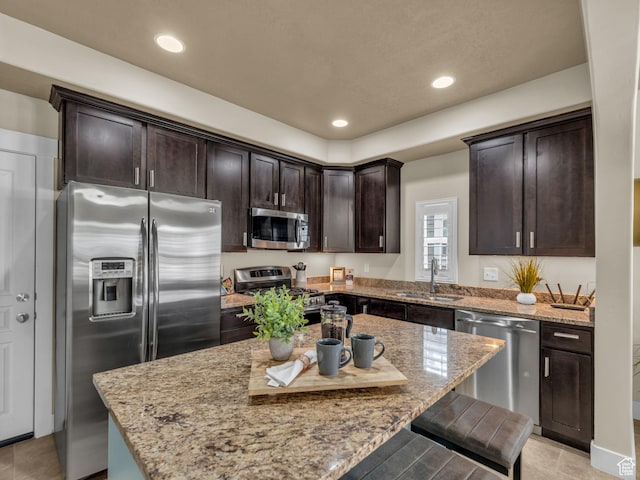 4956 W Vermillion Dr, South Jordan, UT 84009 - kitchen with appliances with stainless steel finishes, dark brown cabinetry, a kitchen breakfast bar, light stone counters, and recessed lighting