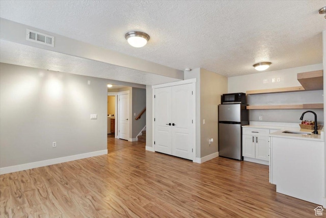 4124 S 3475 W, West Haven, UT 84401 - kitchen featuring freestanding refrigerator, light countertops, a textured ceiling, light wood-style floors, and white cabinets