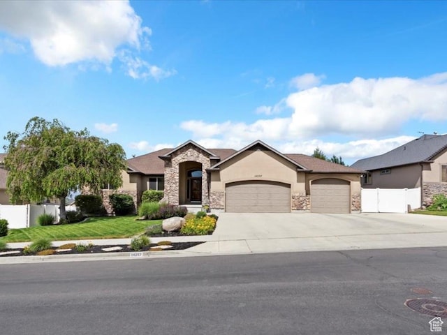14257 S Round Rock Dr W, Herriman, UT 84096 - view of front of house with stone siding, a garage, stucco siding, and concrete driveway