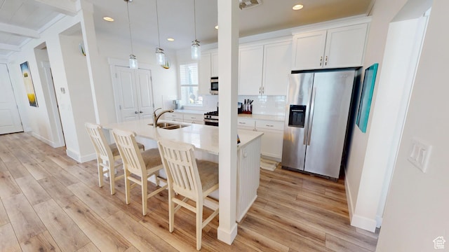 10612 S Lake Ave, South Jordan, UT 84009 - kitchen with stainless steel fridge, recessed lighting, an island with sink, light wood-style floors, and backsplash