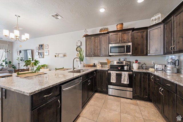 140 W Center St Unit 29, Ivins, UT 84738 - kitchen with stainless steel appliances, a peninsula, light tile patterned floors, light stone counters, and a chandelier