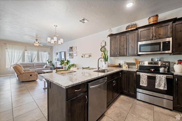 140 W Center St Unit 29, Ivins, UT 84738 - kitchen with appliances with stainless steel finishes, a peninsula, dark brown cabinets, light tile patterned floors, and a textured ceiling