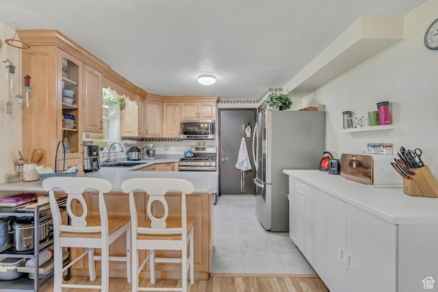 501 N Main St, Vernon, UT 84080 - kitchen featuring stainless steel appliances, a peninsula, a kitchen bar, light brown cabinets, and light countertops