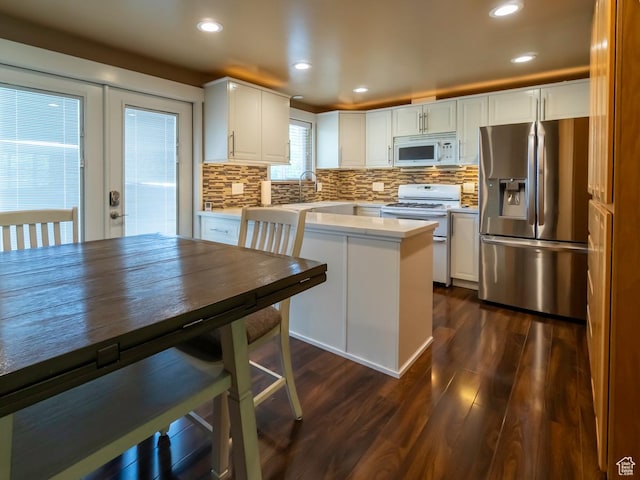 2970 S Mock Orange Dr W, West Valley City, UT 84119 - kitchen featuring white appliances, light countertops, dark wood-style flooring, white cabinets, and decorative backsplash
