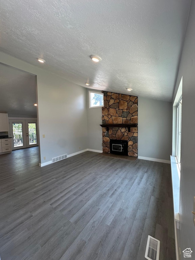 6306 W 3705 S, West Valley City, UT 84128 - unfurnished living room with dark wood-type flooring, a textured ceiling, healthy amount of natural light, a stone fireplace, and french doors