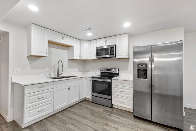 7335 N Harvest Crop Dr, Eagle Mountain, UT 84005 - kitchen with stainless steel appliances, white cabinets, light wood-style flooring, recessed lighting, and light stone countertops
