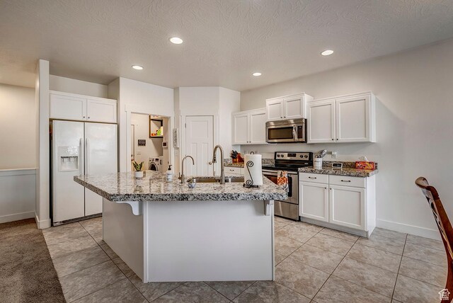 56 N Rue De Matth W, Vineyard, UT 84058 - kitchen featuring appliances with stainless steel finishes, white cabinets, light stone countertops, a center island with sink, and recessed lighting
