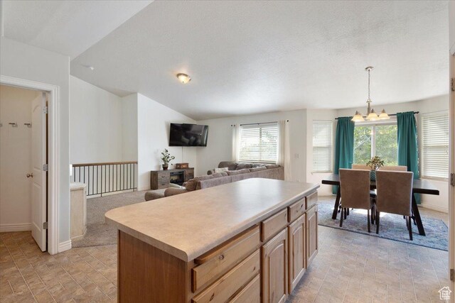 4509 S Greystock Cir W, West Valley City, UT 84120 - kitchen with a chandelier, stone finish floors, light countertops, a center island, and hanging light fixtures