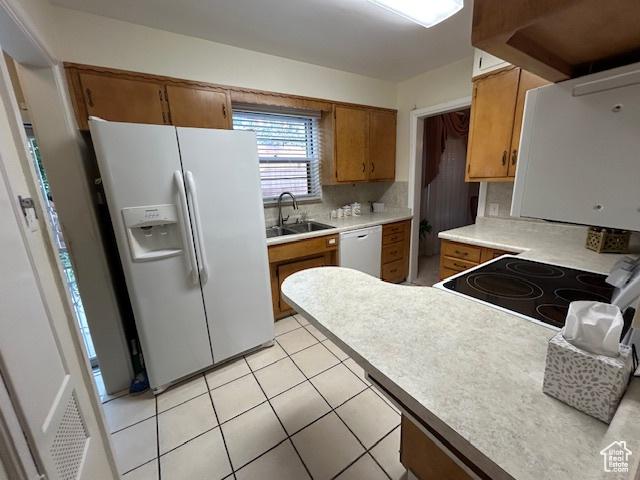 1567 E Westminster Ave, Salt Lake City, UT 84105 - kitchen with white appliances, brown cabinets, decorative backsplash, light countertops, and light tile patterned floors