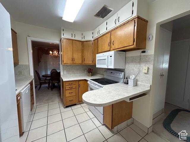 1567 E Westminster Ave, Salt Lake City, UT 84105 - kitchen with white appliances, light countertops, light tile patterned flooring, a peninsula, and a chandelier