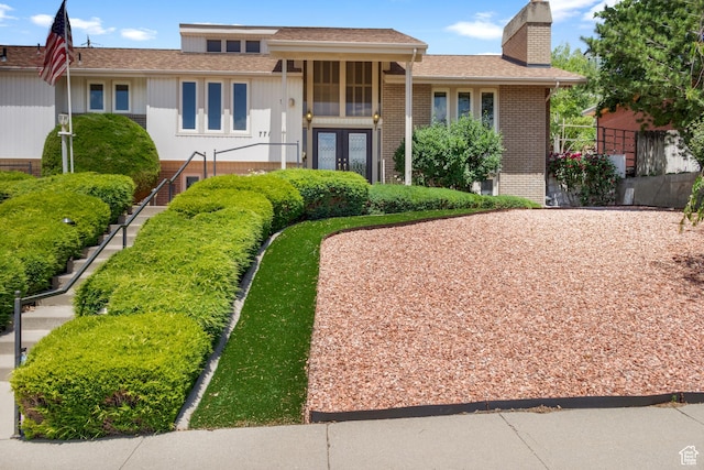 771 E 17th Ave, Salt Lake City, UT 84103 - split level home with brick siding, a chimney, stairs, french doors, and roof with shingles
