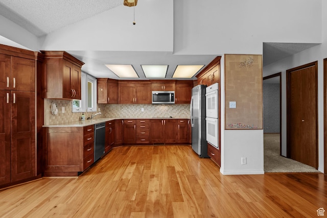 771 E 17th Ave, Salt Lake City, UT 84103 - kitchen with appliances with stainless steel finishes, light wood finished floors, light countertops, lofted ceiling, and tasteful backsplash