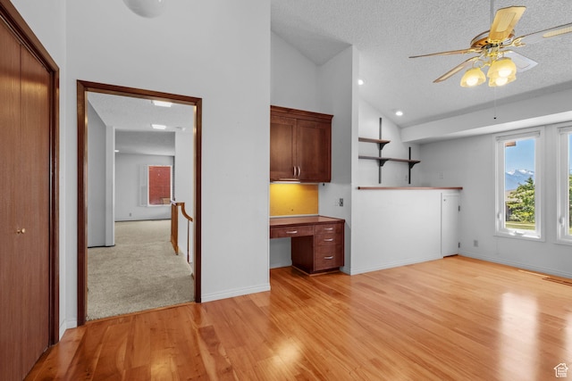 771 E 17th Ave, Salt Lake City, UT 84103 - unfurnished living room with built in desk, a textured ceiling, ceiling fan, light wood-style floors, and high vaulted ceiling