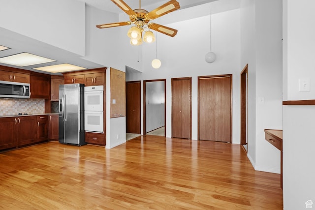 771 E 17th Ave, Salt Lake City, UT 84103 - kitchen with appliances with stainless steel finishes, a high ceiling, ceiling fan, light wood finished floors, and tasteful backsplash