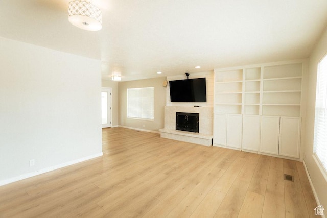 571 E Center St, Kaysville, UT 84037 - unfurnished living room with light wood-type flooring, a fireplace with raised hearth, and healthy amount of natural light