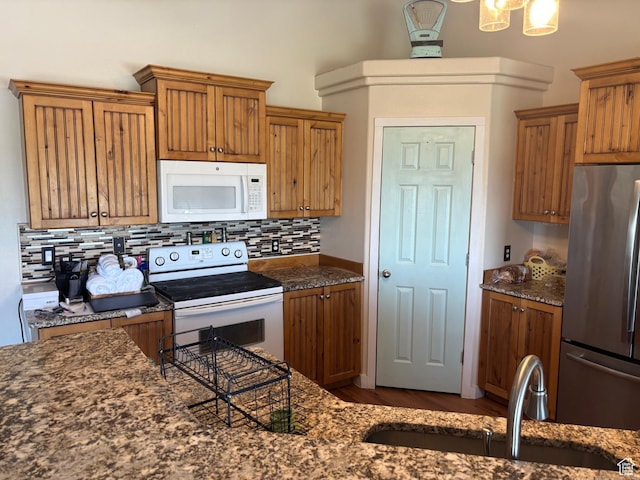 2673 S 2400 W, Weston, ID 83286 - kitchen featuring white appliances, tasteful backsplash, brown cabinetry, dark stone countertops, and wood finished floors