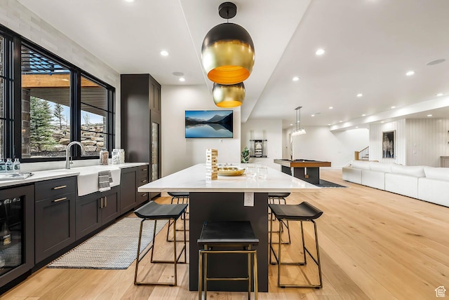 2225 Elk Meadows Cir, Woodland, UT 84036 - kitchen with beverage cooler, light wood-style flooring, a kitchen breakfast bar, open floor plan, and a kitchen island