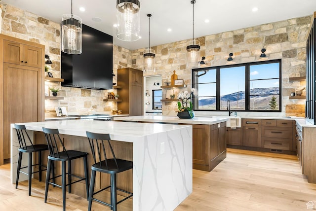 2225 Elk Meadows Cir, Woodland, UT 84036 - kitchen with open shelves, a large island, range hood, light wood-style flooring, and hanging light fixtures