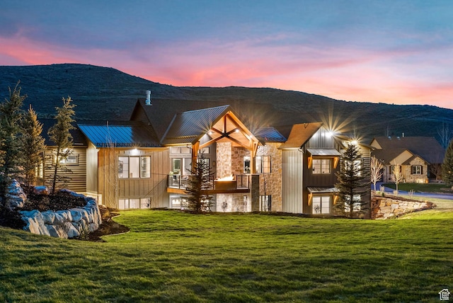 2225 Elk Meadows Cir, Woodland, UT 84036 - back of property at dusk featuring stone siding, board and batten siding, and a lawn