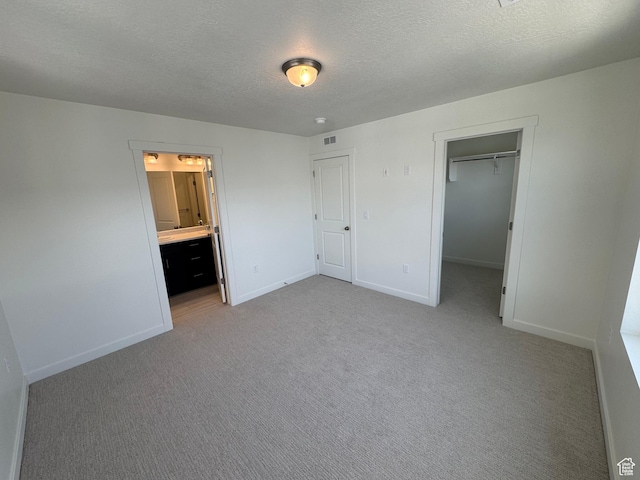 1668 N 1600 W Unit 128, Layton, UT 84041 - unfurnished bedroom featuring carpet flooring, a textured ceiling, a spacious closet, connected bathroom, and a closet