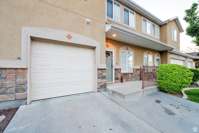 8728 S Black Diamond Cv W, West Jordan, UT 84081 - view of front facade with stucco siding, concrete driveway, stone siding, and an attached garage