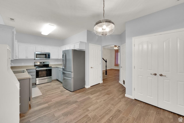 8728 S Black Diamond Cv W, West Jordan, UT 84081 - kitchen with stainless steel appliances, light countertops, light wood-style flooring, white cabinets, and pendant lighting