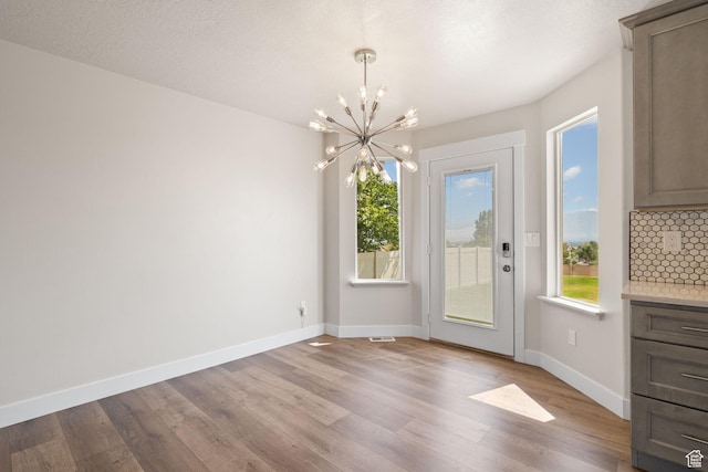 6959 S Adventure Way, West Jordan, UT 84081 - unfurnished dining area with a chandelier, wood finished floors, and plenty of natural light