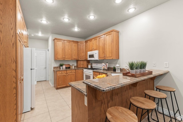 11863 S Cottage Side Way, Draper, UT 84020 - kitchen with white appliances, a peninsula, a breakfast bar area, recessed lighting, and light tile patterned flooring