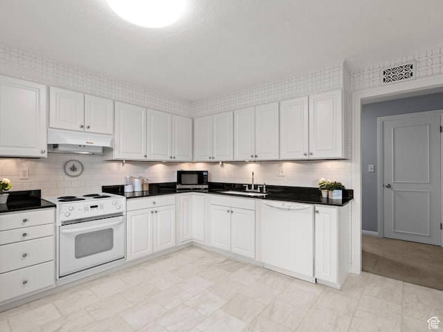 1150 E 2700 S Unit 50G, Salt Lake City, UT 84106 - kitchen featuring white appliances, under cabinet range hood, dark countertops, backsplash, and white cabinetry
