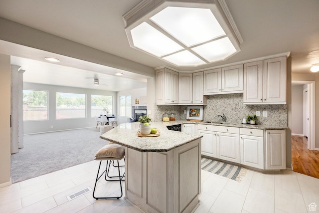 8097 S 535 E, Sandy, UT 84070 - kitchen featuring light colored carpet, open floor plan, a peninsula, light stone counters, and decorative backsplash