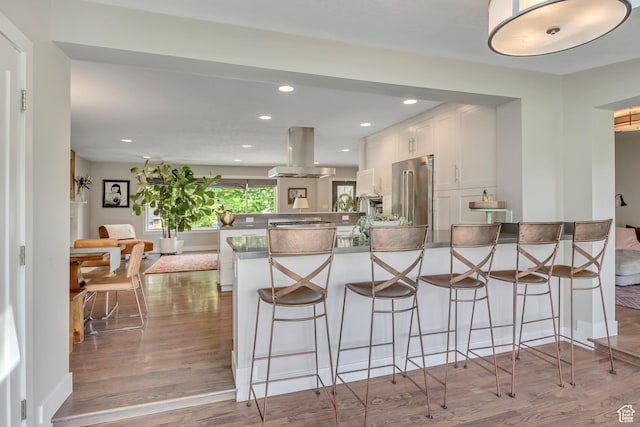 2241 E Melodie Ann Way, Holladay, UT 84124 - kitchen featuring a peninsula, island range hood, stainless steel appliances, white cabinetry, and wood finished floors