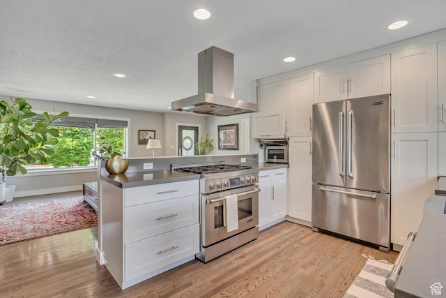 2241 E Melodie Ann Way, Holladay, UT 84124 - kitchen with high end appliances, island range hood, white cabinets, light wood finished floors, and a peninsula