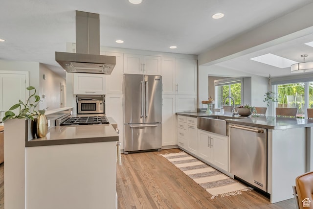 2241 E Melodie Ann Way, Holladay, UT 84124 - kitchen with appliances with stainless steel finishes, island exhaust hood, a peninsula, light wood-style flooring, and white cabinetry