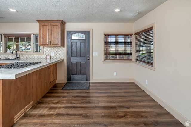 210 S 100 E, Fielding, UT 84311 - kitchen with brown cabinetry, dark wood-type flooring, a textured ceiling, tasteful backsplash, and recessed lighting