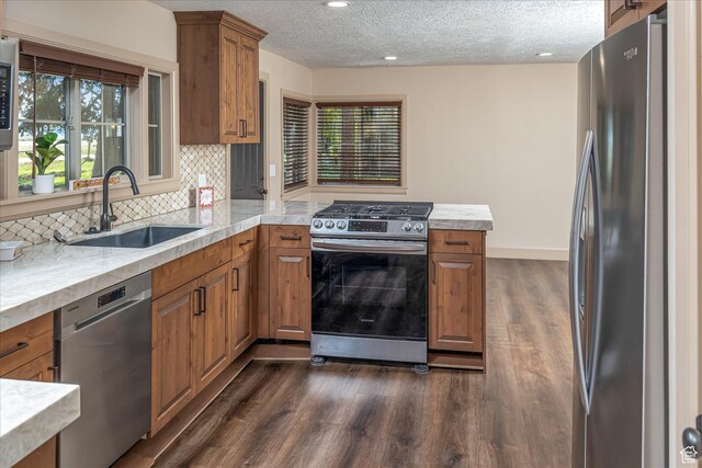 210 S 100 E, Fielding, UT 84311 - kitchen with appliances with stainless steel finishes, brown cabinets, dark wood-style flooring, a peninsula, and a textured ceiling