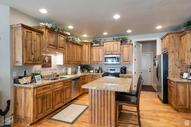 258 E Red Leaf Dr, Draper, UT 84020 - kitchen featuring appliances with stainless steel finishes, a kitchen island, recessed lighting, light wood-style floors, and light stone counters