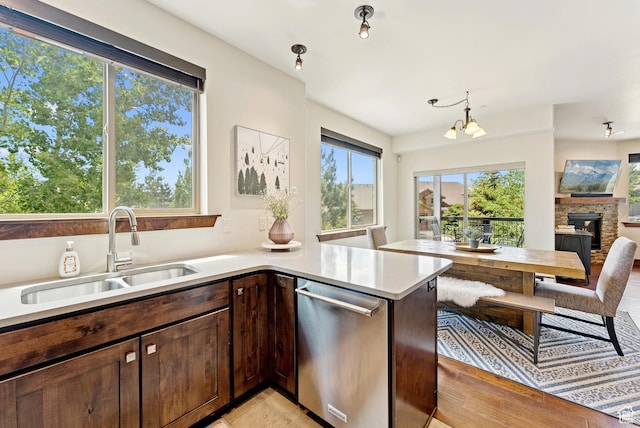 14275 N Buck Horn Trl Unit 41-F, Kamas, UT 84036 - kitchen with stainless steel dishwasher, light countertops, open floor plan, dark brown cabinetry, and a stone fireplace