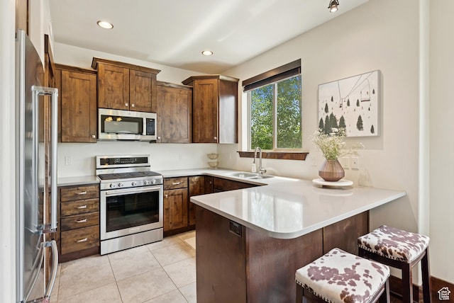 14275 N Buck Horn Trl Unit 41-F, Kamas, UT 84036 - kitchen with stainless steel appliances, a peninsula, light countertops, a kitchen breakfast bar, and light tile patterned floors
