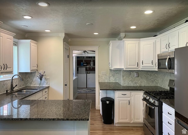 12900 S 2200 W, Riverton, UT 84065 - kitchen featuring appliances with stainless steel finishes, washing machine and dryer, white cabinetry, wood finished floors, and ornamental molding