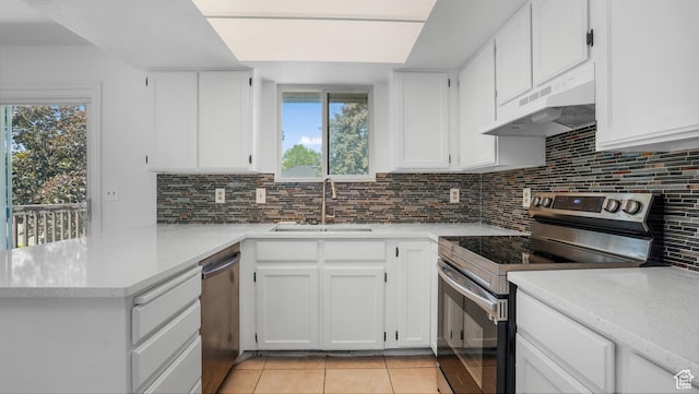 607 N 2000 W, West Point, UT 84015 - kitchen with appliances with stainless steel finishes, under cabinet range hood, a peninsula, light tile patterned floors, and white cabinetry