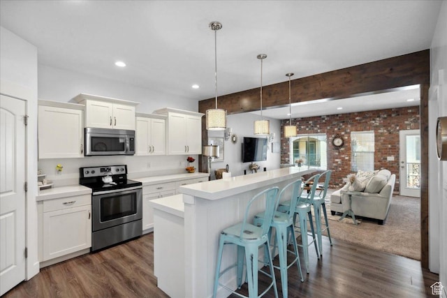 5538 N Turin Ln, Highland, UT 84003 - kitchen featuring appliances with stainless steel finishes, brick wall, a kitchen island, a kitchen breakfast bar, and dark wood-style floors
