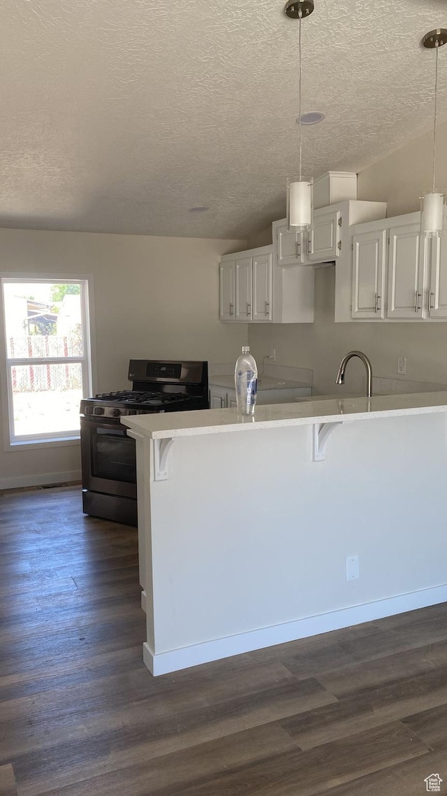 371 Broadmoor Ave, Ogden, UT 84404 - kitchen featuring stainless steel gas stove, a textured ceiling, a kitchen bar, dark wood-type flooring, and white cabinets