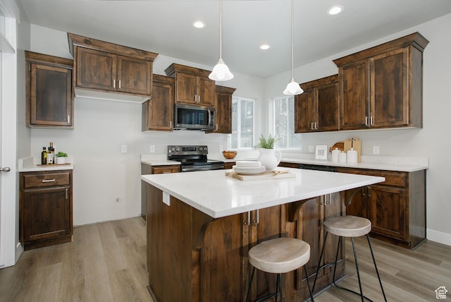 5001 W Anegada Ln S, Herriman, UT 84096 - kitchen with appliances with stainless steel finishes, light wood-style flooring, a kitchen island, a breakfast bar area, and recessed lighting
