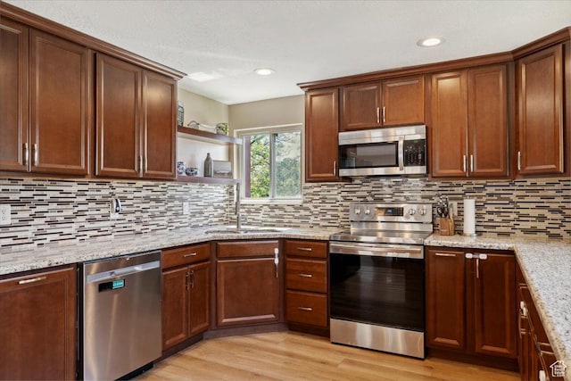 1260 E 2925 N, North Ogden, UT 84414 - kitchen featuring appliances with stainless steel finishes, tasteful backsplash, light stone countertops, open shelves, and light wood finished floors
