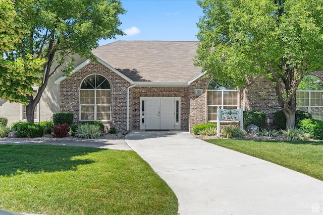 3304 S Hunter Villa Ln Unit D, West Valley City, UT 84128 - view of front of home featuring brick siding, a front lawn, driveway, and a shingled roof