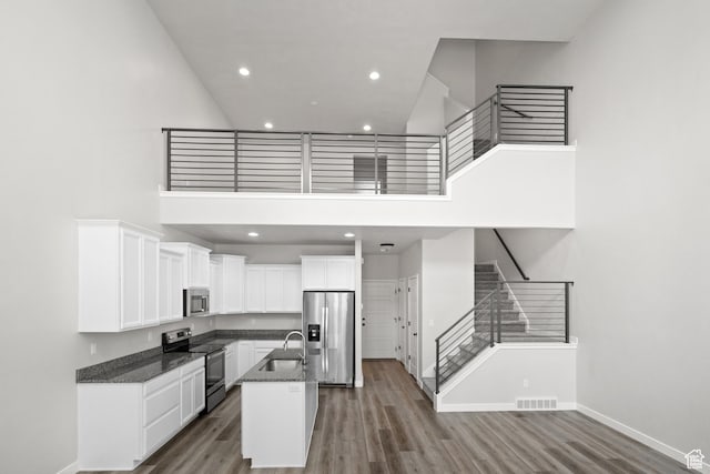 15040 S Wild Horse Way, Bluffdale, UT 84065 - kitchen with appliances with stainless steel finishes, a high ceiling, white cabinetry, wood finished floors, and a kitchen island with sink