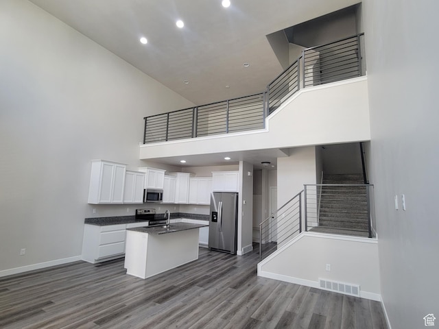 15040 S Wild Horse Way, Bluffdale, UT 84065 - kitchen with stainless steel appliances, a towering ceiling, dark countertops, open floor plan, and white cabinetry