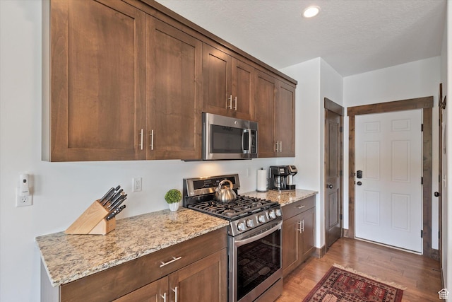 1076 W Abigail Dr, Kamas, UT 84036 - kitchen with stainless steel appliances, light wood finished floors, light stone counters, recessed lighting, and a textured ceiling