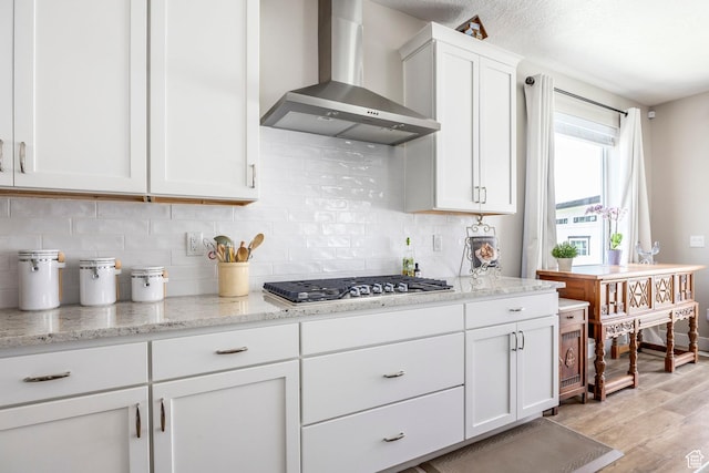 1681 S 1110 E, Heber City, UT 84032 - kitchen featuring wall chimney range hood, stainless steel gas stovetop, light wood finished floors, white cabinetry, and decorative backsplash