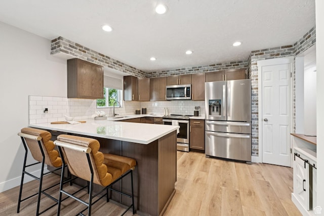 2104 W Champagne Cir, Taylorsville, UT 84129 - kitchen with appliances with stainless steel finishes, a peninsula, backsplash, light countertops, and recessed lighting